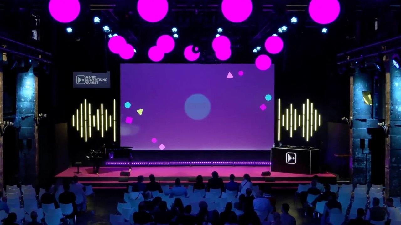 Bühne des Radio Advertising Summit mit Publikum, Standbild aus der Video-Präsentation
